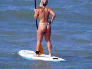 Fetching rump in g-string bathing suit on surfboard.